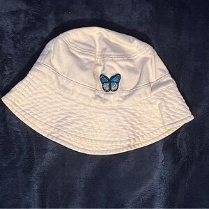 Off-white bucket hat with blue ombré butterfly on the front.